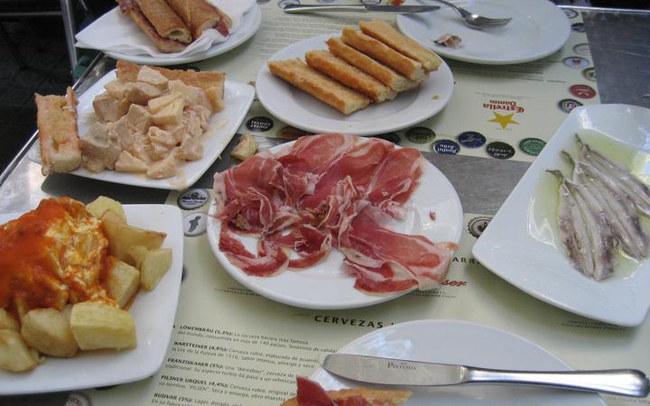 Een tafel met Spaanse tapas, waaronder patatas bravas, pa amb tomàquet en kroketten